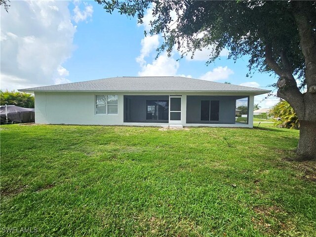 1221 SW 10th Ter, Cape Coral, FL 33991 - rear view of house featuring a lawn, stucco siding, and a sunroom