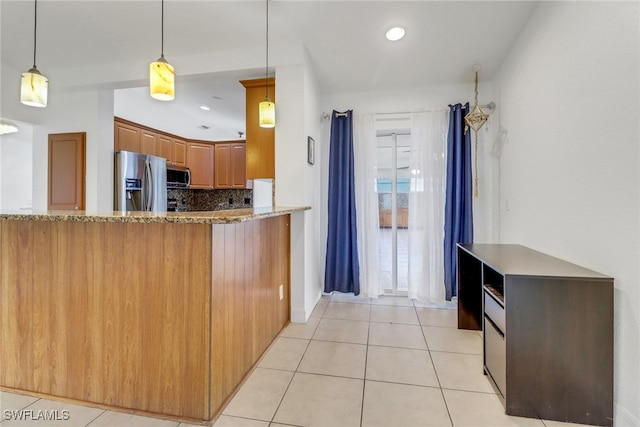 1622 SE 20th St, Cape Coral, FL 33990 - kitchen featuring appliances with stainless steel finishes, light tile patterned floors, brown cabinets, decorative backsplash, and stone countertops