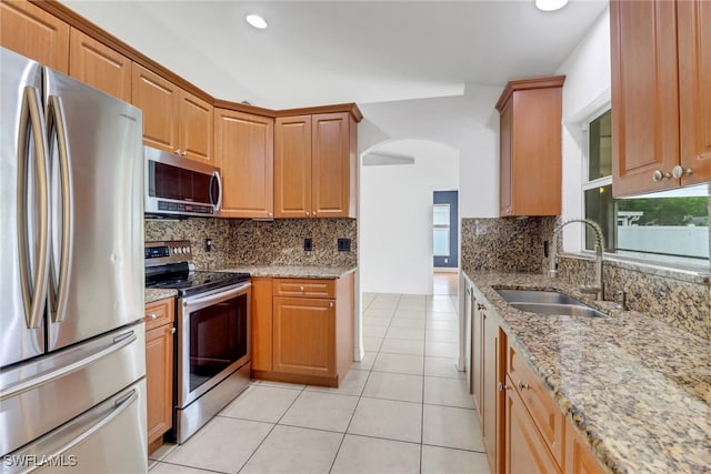 1622 SE 20th St, Cape Coral, FL 33990 - kitchen featuring appliances with stainless steel finishes, a sink, arched walkways, light stone counters, and light tile patterned floors