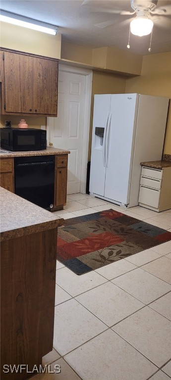 2325 55th Ter SW, Naples, FL 34116 - kitchen featuring black appliances, light tile patterned floors, light countertops, and brown cabinetry