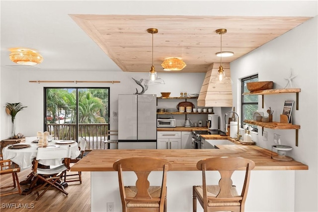 4805 Gary Rd, Bonita Springs, FL 34134 - kitchen featuring freestanding refrigerator, wooden counters, open shelves, premium range hood, and wood finished floors