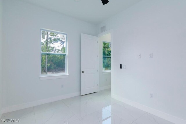 2501 26th St W, Lehigh Acres, FL 33971 - spare room featuring healthy amount of natural light, ceiling fan, and light marble finish flooring