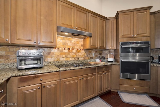 1640 Golden Gate Blvd W, Naples, FL 34117 - kitchen featuring under cabinet range hood, double oven, black electric stovetop, decorative backsplash, and light stone countertops
