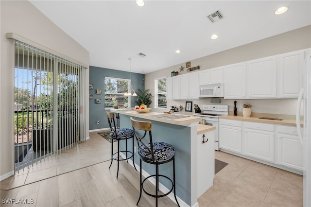 28220 Caballero Way Unit 2422, Bonita Springs, FL 34135 - kitchen with white appliances, white cabinetry, a kitchen breakfast bar, a center island, and baseboards