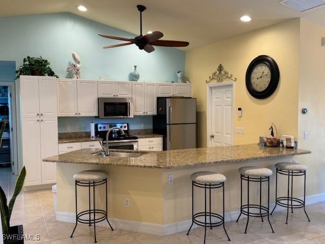 1505 NW 33rd Pl, Cape Coral, FL 33993 - kitchen featuring stainless steel appliances, vaulted ceiling, ceiling fan, a breakfast bar area, and stone countertops