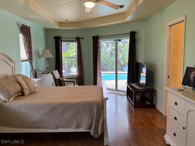 1505 NW 33rd Pl, Cape Coral, FL 33993 - bedroom featuring a raised ceiling, access to outside, dark wood-style flooring, and ceiling fan