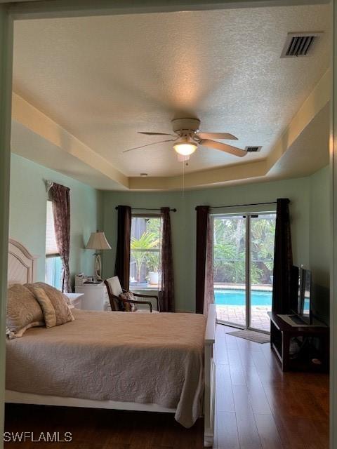 1505 NW 33rd Pl, Cape Coral, FL 33993 - bedroom featuring access to exterior, a raised ceiling, wood finished floors, and a textured ceiling