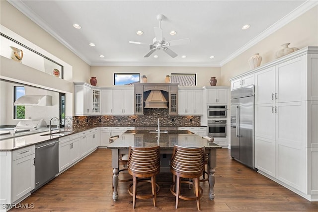 11950 Heather Woods Ct, Naples, FL 34120 - kitchen with appliances with stainless steel finishes, a sink, custom range hood, plenty of natural light, and ornamental molding