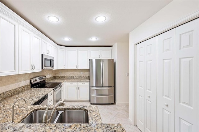 6637 Alden Woods Cir Unit 102, Naples, FL 34113 - kitchen featuring appliances with stainless steel finishes, a sink, white cabinetry, light stone counters, and recessed lighting