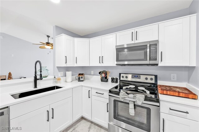 628 SW 9th Ave, Cape Coral, FL 33991 - kitchen with stainless steel appliances, a sink, ceiling fan, white cabinetry, and light countertops