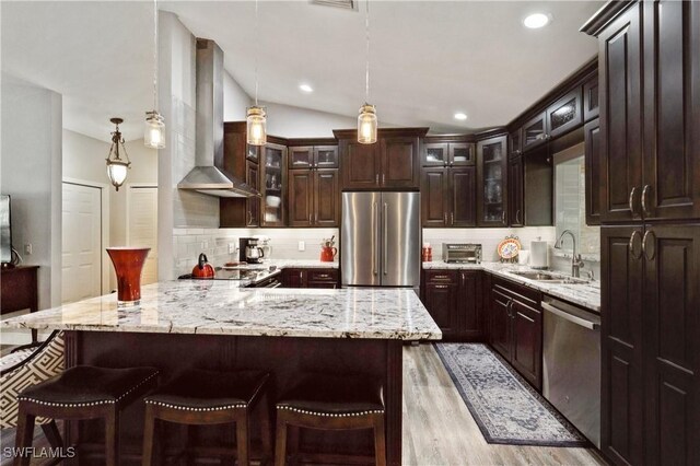 1440 14th Ave NE, Naples, FL 34120 - kitchen featuring appliances with stainless steel finishes, wall chimney exhaust hood, a kitchen breakfast bar, light wood-type flooring, and recessed lighting