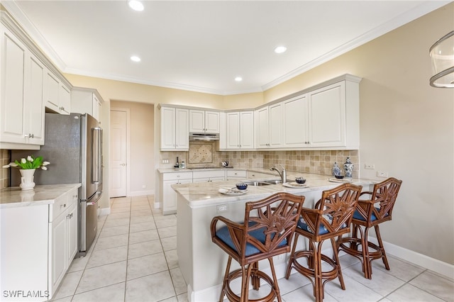 3051 Lancaster Dr Unit 4, Naples, FL 34105 - kitchen featuring a peninsula, freestanding refrigerator, a kitchen bar, tasteful backsplash, and under cabinet range hood