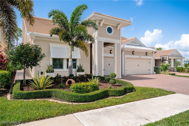 view of front facade featuring decorative driveway, an attached garage, and stucco siding