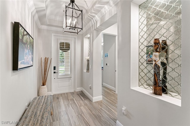 foyer with a chandelier, crown molding, and wood finished floors