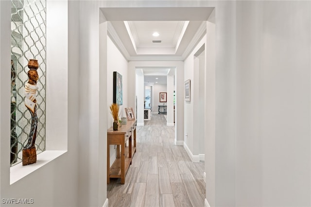 hall with ornamental molding, a tray ceiling, light wood-style floors, and recessed lighting