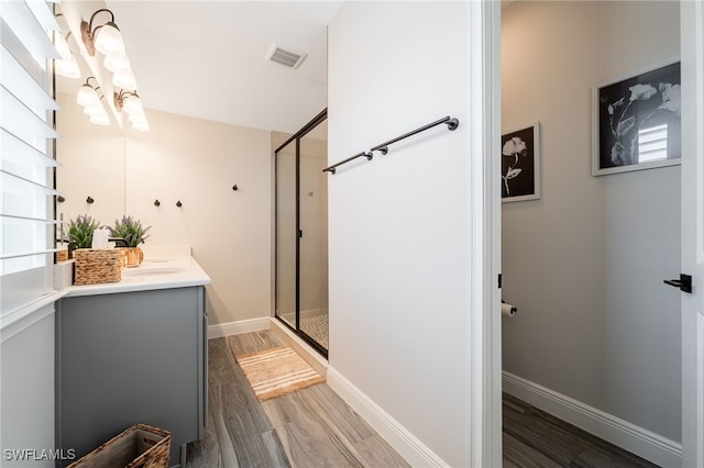 bathroom featuring vanity, a stall shower, and wood finished floors