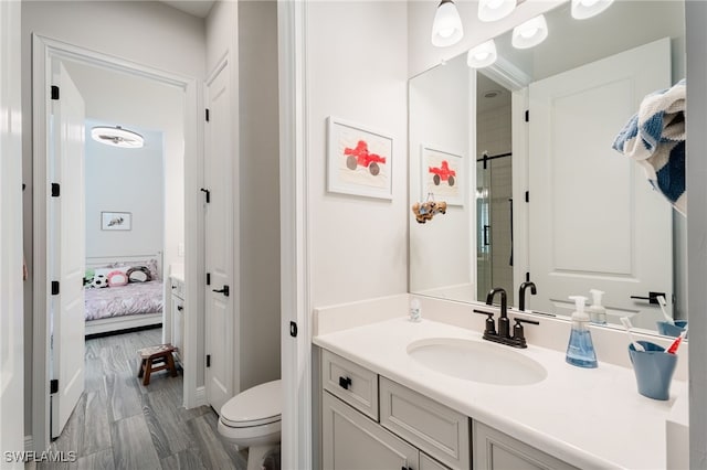 ensuite bathroom with vanity, a shower with door, and wood finished floors