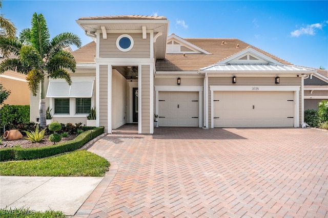 view of front of home with decorative driveway, a tile roof, and an attached garage