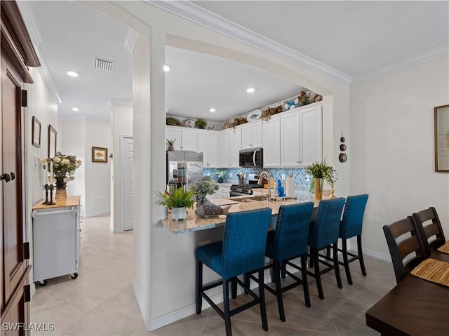 17857 Woodland Ct, Punta Gorda, FL 33982 - kitchen with appliances with stainless steel finishes, decorative backsplash, white cabinetry, a peninsula, and a kitchen breakfast bar