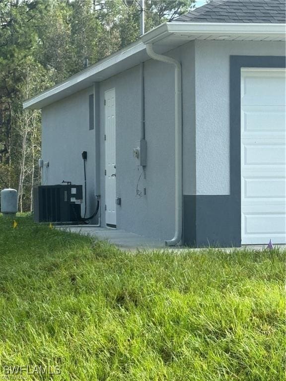 3003 18th St W, Lehigh Acres, FL 33976 - view of side of property featuring stucco siding, a shingled roof, and central AC