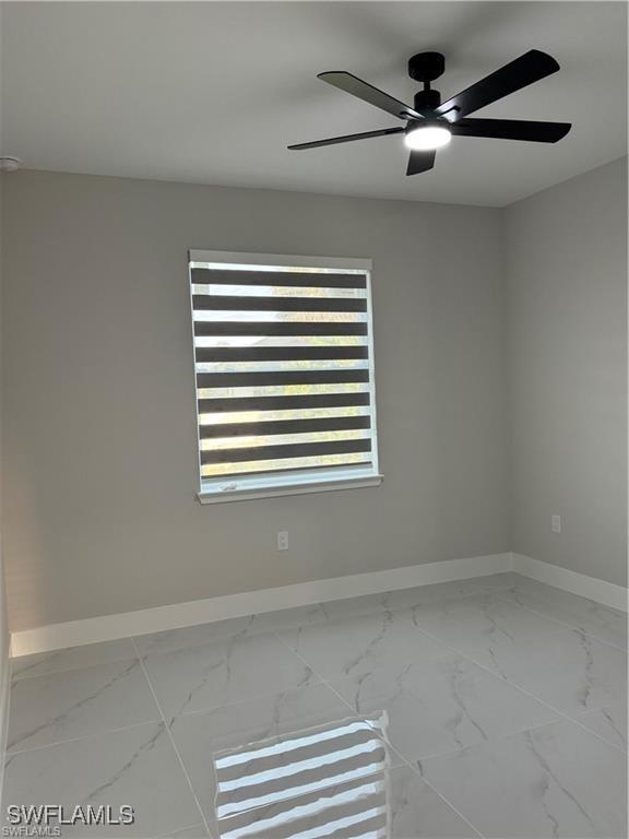 3003 18th St W, Lehigh Acres, FL 33976 - spare room featuring baseboards, marble look tile flooring, and ceiling fan