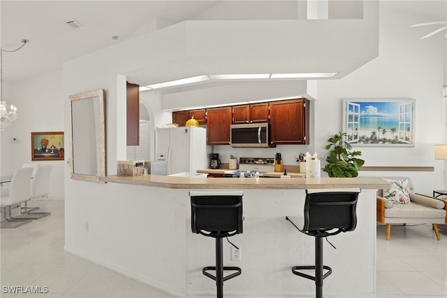 3925 Oasis Blvd, Cape Coral, FL 33914 - kitchen with white refrigerator with ice dispenser, stainless steel microwave, light tile patterned floors, light countertops, and a kitchen bar