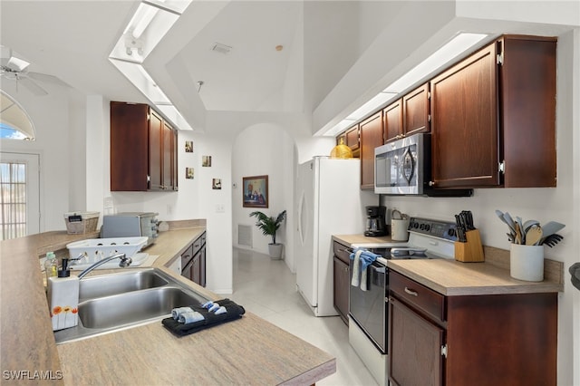 3925 Oasis Blvd, Cape Coral, FL 33914 - kitchen featuring white appliances, light tile patterned flooring, ceiling fan, arched walkways, and light countertops