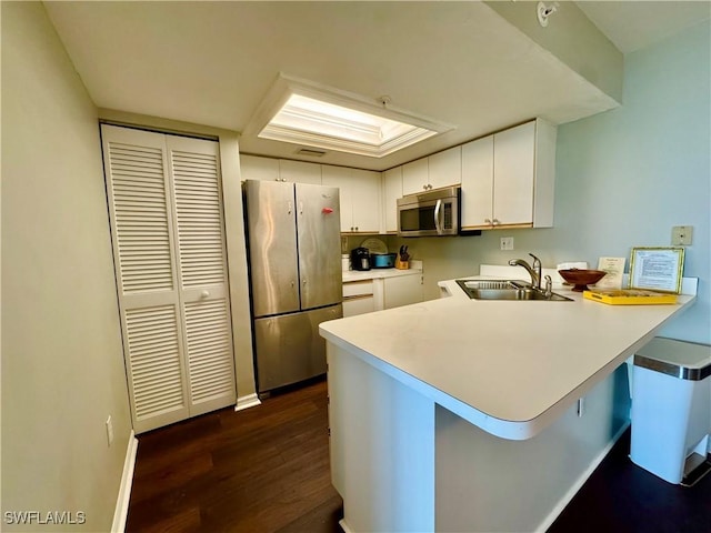 7390 Estero Blvd Unit 702, Fort Myers Beach, FL 33931 - kitchen featuring stainless steel appliances, a peninsula, dark wood-style floors, white cabinetry, and light countertops