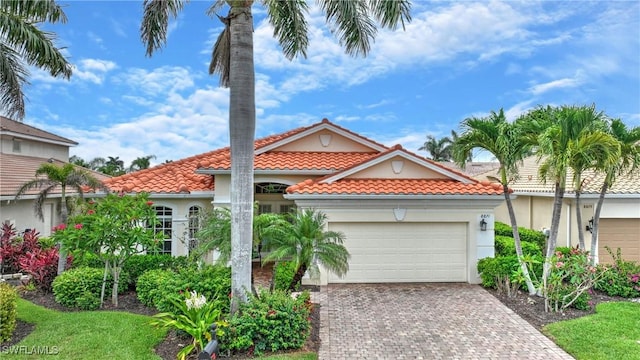 8871 Biella Ct, Estero, FL 33967 - mediterranean / spanish house featuring a garage, decorative driveway, a tile roof, and stucco siding