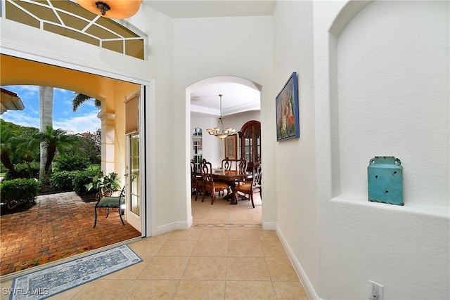 8871 Biella Ct, Estero, FL 33967 - hallway with a chandelier, tile patterned flooring, arched walkways, and baseboards