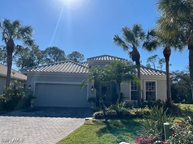 16156 Parque Ln, Naples, FL 34110 - mediterranean / spanish house with a tiled roof, a garage, decorative driveway, and stucco siding