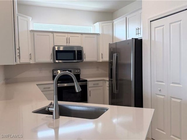 2011 Vermont Ln, Naples, FL 34120 - kitchen with stainless steel appliances, white cabinets, light countertops, and a sink
