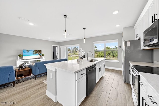 2008 NW 24th Pl, Cape Coral, FL 33993 - kitchen featuring appliances with stainless steel finishes, wood tiled floors, open floor plan, a center island with sink, and white cabinetry