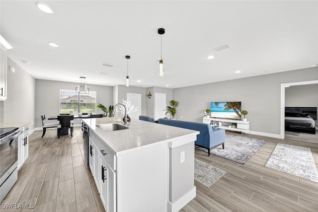 2008 NW 24th Pl, Cape Coral, FL 33993 - kitchen with stainless steel appliances, light wood-style floors, a kitchen island with sink, white cabinetry, and open floor plan
