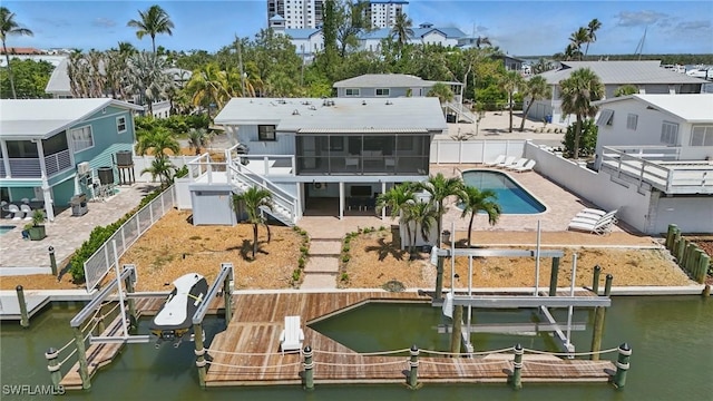 370 Bayland Rd, Fort Myers Beach, FL 33931 - rear view of house with boat lift, a sunroom, a fenced backyard, and a water view
