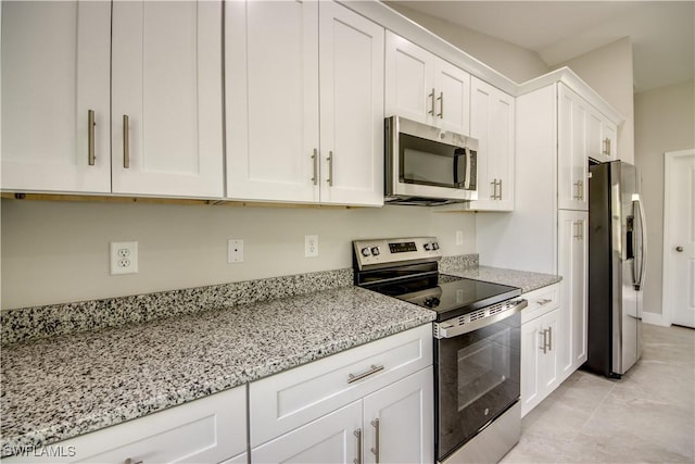 4114 2nd St SW, Lehigh Acres, FL 33976 - kitchen with stainless steel appliances, white cabinetry, light stone countertops, and light tile patterned flooring
