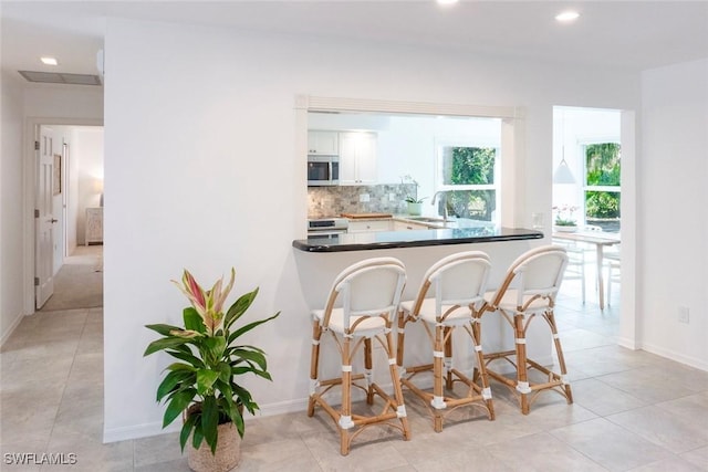 3430 27th Ave SW, Naples, FL 34117 - kitchen featuring stainless steel microwave, a sink, range, tasteful backsplash, and light tile patterned floors