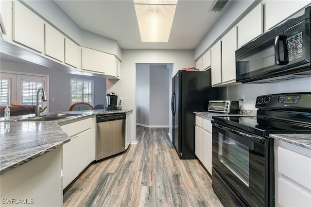 950 Moody Rd Unit 124, North Fort Myers, FL 33903 - kitchen featuring black appliances, a sink, light wood-style flooring, white cabinetry, and a peninsula