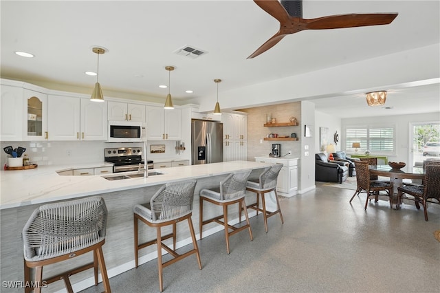 2749 Bruce St, Matlacha, FL 33993 - kitchen with appliances with stainless steel finishes, a peninsula, a breakfast bar area, decorative backsplash, and white cabinetry