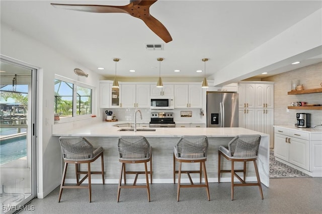 2749 Bruce St, Matlacha, FL 33993 - kitchen featuring stainless steel appliances, a peninsula, open shelves, a kitchen bar, and white cabinets