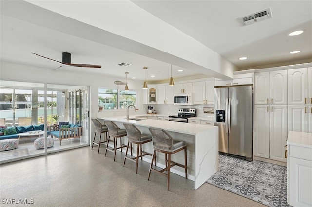 2749 Bruce St, Matlacha, FL 33993 - kitchen featuring stainless steel appliances, a peninsula, a kitchen breakfast bar, white cabinetry, and a ceiling fan