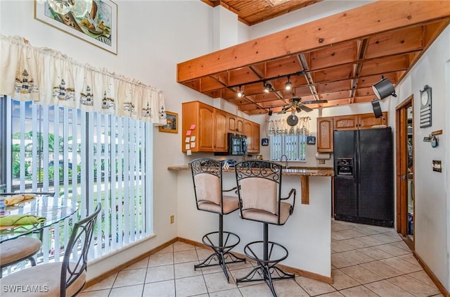7786 Breakwater Ct, Bokeelia, FL 33922 - kitchen featuring black appliances, light tile patterned flooring, a peninsula, a kitchen bar, and a wood ceiling with exposed beams