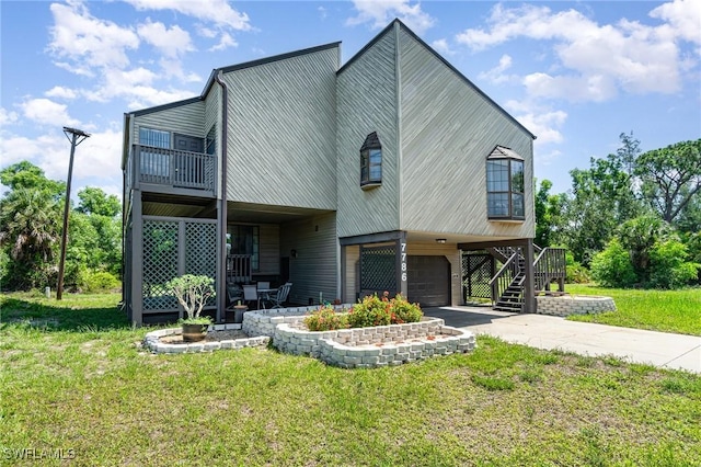 7786 Breakwater Ct, Bokeelia, FL 33922 - view of front of property with a front yard, an attached garage, concrete driveway, stairs, and a balcony