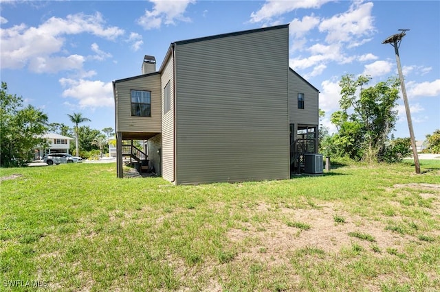 7786 Breakwater Ct, Bokeelia, FL 33922 - view of side of home with stairway, a yard, and a chimney