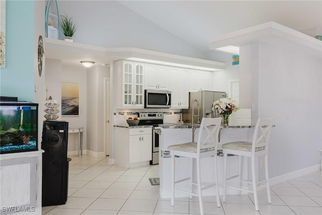 1525 SW 43rd Ter, Cape Coral, FL 33914 - kitchen featuring stainless steel appliances, glass insert cabinets, white cabinets, a kitchen bar, and light tile patterned floors