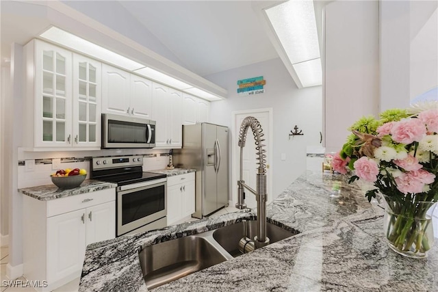 1525 SW 43rd Ter, Cape Coral, FL 33914 - kitchen featuring stainless steel appliances, a sink, light stone counters, glass insert cabinets, and white cabinetry