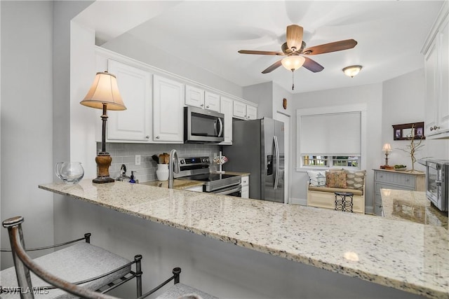 10020 Maddox Ln Unit 113, Bonita Springs, FL 34135 - kitchen featuring appliances with stainless steel finishes, tasteful backsplash, a ceiling fan, and light stone countertops