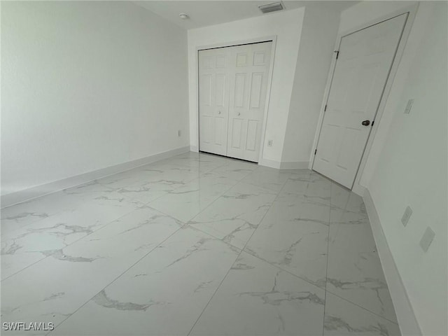 3508 17th St SW, Lehigh Acres, FL 33976 - unfurnished bedroom featuring baseboards, light marble finish flooring, and a closet