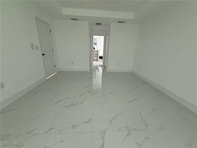 3508 17th St SW, Lehigh Acres, FL 33976 - unfurnished room with baseboards, light marble finish floors, and a tray ceiling