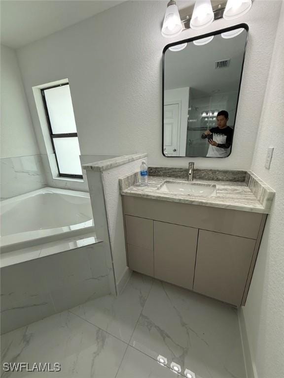 3508 17th St SW, Lehigh Acres, FL 33976 - bathroom featuring vanity, a garden tub, marble look tiles, and healthy amount of natural light